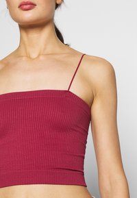 Burgundy ribbad crop top med tunna spagettiband och en figurnära design, i ett strukturerat tyg och med rak nederkant.