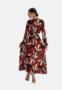 Maxi jurk met een bloemenpatroon in rood, beige en zwart. Lange mouwen met ruches aan de manchetten en een ceintuur om de taille. Gladde, lichte stof.