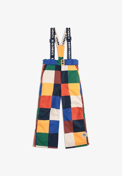 Farbenfrohe, gemusterte Latzhosen mit verstellbaren blauen Trägern, einem Knopfverschluss und quadratischen Patches in Rot, Gelb, Grün und Blau.