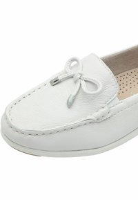 Mocasín blanco de cuero con detalles cosidos, puntera redonda, cordón decorativo atado con puntas metálicas y plantilla acolchada perforada.