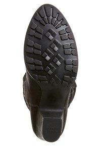 Czarna gumowa podeszwa ma teksturowany wzór z geometrycznymi kształtami. Górna część buta jest wykonana z zamszu, z przeszyciami wzdłuż boków.