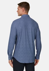 Blauw overhemd met lange mouwen van een gestructureerde stof, afgeronde zoom, manchetten met knopen en een klassieke kraag, gezien vanaf de achterkant.