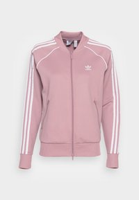 Rosa Adidas zip-jacka med vita tre ränder på ärmarna, dragkedjefickor, ribbade manschetter och Adidas-logotyp på vänster bröst.