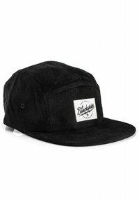 Gorra de pana negra con visera plana, que presenta un parche de logo blanco en la parte frontal y un diseño de seis paneles con ventilaciones de ojales.