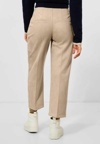 Beige, skräddarsydda, högmidjade byxor i ett mockaliknande tyg. Har bakfickor, raka ben och en mjuk textur.