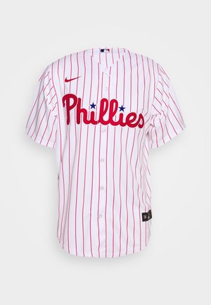 Maillot de baseball blanc des Philadelphia Phillies avec fines rayures rouges, logo rouge en écriture cursive avec étoiles bleues, et ouverture à boutons sur le devant.