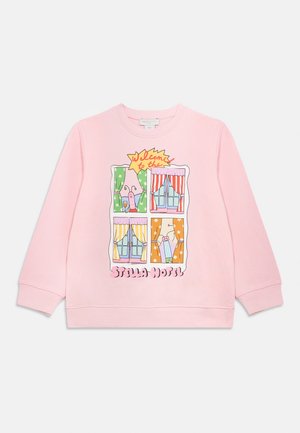 Roze sweatvest met een cartoonontwerp van ramen, gordijnen en personages. De tekst luidt "Welkom in het Stella Hotel."