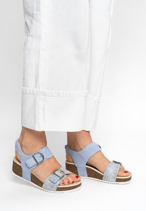 Light blue wedge sandals with a textured upper, adjustable ankle straps, and a decorative buckle on the front. White rubber sole.