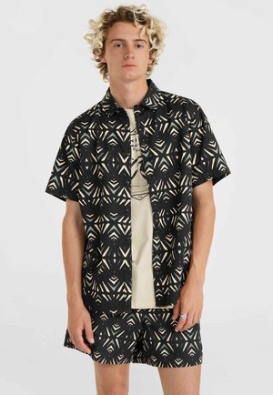 Korte mouwen zwarte shirt met geometrisch crème patroon, gecombineerd met bijpassende shorts. Gemaakt van lichtgewicht stof, met knopen en een kraag.