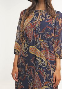 Mörkblå klänning med paisleymönster i orange, gult och vitt. Genomskinligt, lätt material med trekvartsärmar och elastisk midja.
