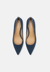 Navy blue suede pointed-toe pumps with a smooth tan interior and small back zipper detail, featuring a sleek, modern silhouette.