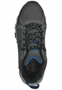 Zapatilla negra y gris con parte superior de malla, detalles en azul claro y cordones negros. Presenta un diseño impermeable y una suela texturizada.