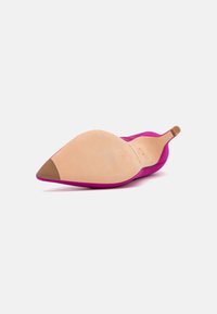 Scarpa con tacco alto in suede rosa, con punta affusolata e suola in pelle color nude, dotata di un piccolo tassello sul retro e un design elegante.