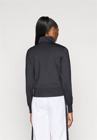 Černá mikina s vysokým límcem a dlouhými rukávy, žebrovaným lemem a hladkou strukturou. Má přiléhavý střih, zobrazeno zezadu.