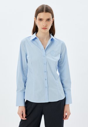 Camicia azzurro chiaro con bottoni realizzata in tessuto liscio, dotata di colletto a punta, maniche lunghe e logo ricamato sul petto.