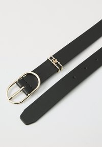 Ceinture en cuir noir avec une boucle en métal doré présentant un accent géométrique, texture lisse et trous régulièrement espacés pour le réglage.