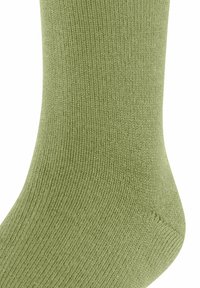 Zbliżenie na teksturowan�ą zieloną skarpetę, podkreślające jej miękką tkaninę i wzór dzianiny. Widoczne są strefy kostki i pięty, co uwydatnia projekt.