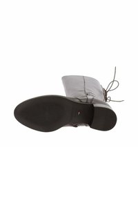 Bruine leren enkellaars met een ronde neus, een getextureerde zwarte rubberen zool en vetersluiting aan de achterkant. Glad oppervlak met subtiele stikselaccenten.