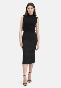 Haut sans manches noir à côtes avec col montant, associé à une jupe crayon noire ajustée. L'ensemble présente un design élégant et des talons à brides de cheville.