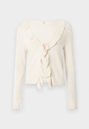 Krēmkrāsas garroku kardigans ar ribotu tekstūru un volānveida V veida izgriezumu ar sasiešanas aizdari priekšpusē.