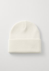 Hvit strikket lue med ribbet design, myk tekstur og glatt overflate. Har en avrundet topp og ribbestrikket søm.