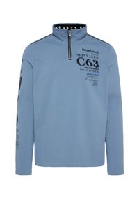 Pullover azzurro chiaro con collo a zip, maniche lunghe e testo stampato in nero. Presenta due strisce nere sulle spalle. Realizzato in morbido cotone misto.
