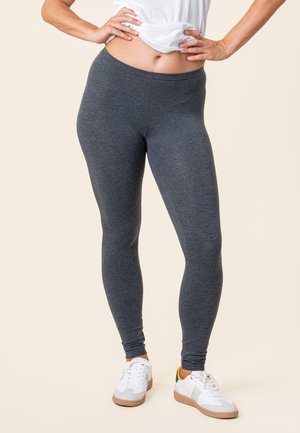 Gray leggings made of soft, stretchy material, fitted design, mid-rise waist, paired with white sneakers. Plain background.