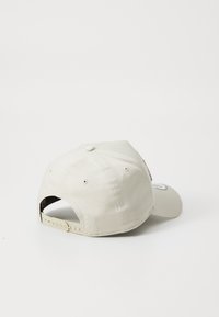 Khaki baseball cap med en buet skygge, justerbar rem, stofcenterpanel og broderet logo på bagsiden. Glat overflade.