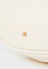 Sac à main blanc texturé avec un motif en diamant et un accent logo doré. Bords lisses avec un léger éclat, fabriqué à partir d'un matériau tissé.