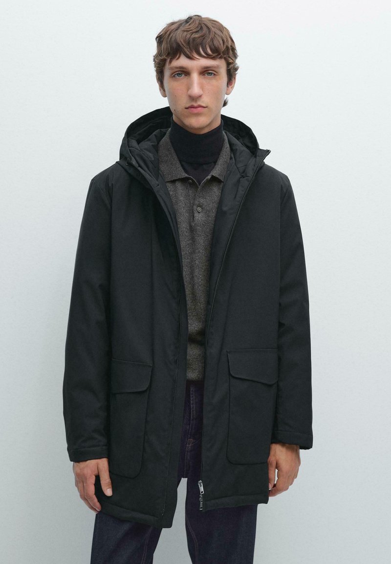 Schwarze gefütterte Parka mit Kapuze, ausgestattet mit zwei aufgesetzten Fronttaschen, einem Reißverschluss und einer glatten Oberflächenstruktur.