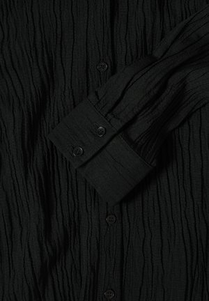 Czarna, pomarszczona koszula z guzikiem, wykonana z teksturowanej tkaniny, z długimi rękawami oraz czarnymi guzikami przy mankietach i na przodzie.