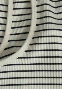 Top in tessuto a coste di colore bianco sporco con strisce orizzontali nere, caratterizzato da un colletto arrotondato e una texture morbida.