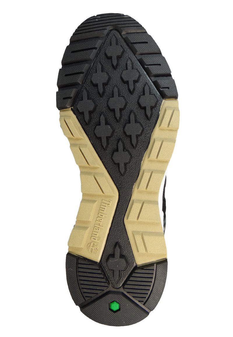 Suola in gomma nera e marrone con battistrada texturizzato, caratterizzata da un motivo geometrico a croci e un accento verde vicino al tallone.