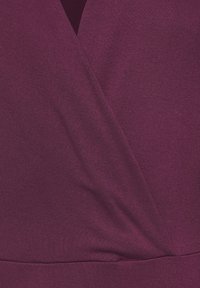 Deep maroon fabric with a smooth texture, featuring a wrap design and subtle draping detail, seamlessly transitioning at the hem.