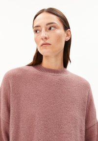 Hellrosa Pullover aus weichem Strickmaterial. Hat einen runden Halsausschnitt und eine lässige Passform mit abgesenkten Schultern und langen Ärmeln.