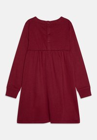 Abito a maniche lunghe color bordeaux con scollatura rotonda, vita arricciata e tre bottoni sul retro. Realizzato in un tessuto morbido e elasticizzato con una texture liscia.