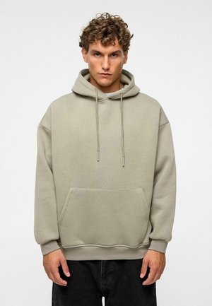 Beige hoodie met een kangoeroe zak aan de voorkant, trekkoorden en opgerolde mouwen. De stof heeft een gladde textuur en een comfortabele pasvorm.