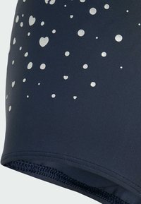 Shorts de bain bleu marine avec des motifs en forme de cœur et de points argentés, présentant une texture lisse et une taille cousue.