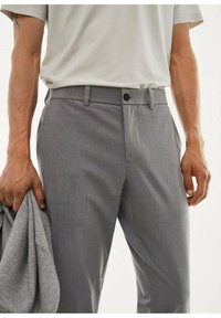 Szare, dopasowane spodnie garniturowe o fakturowanym wykończeniu, z ciasnym krojem, zapięciem na guziki i bocznymi kieszeniami. Noszone z jasnoszarą koszulą.