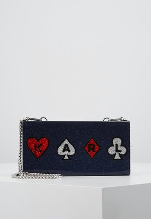 Navy blue glitter handbag with silver chain strap, featuring decorative playing card symbols: red heart, black spade, red diamond, and black club.