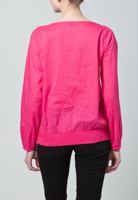 Rosa långärmad blus med avslappnad passform, med rund halsringning och elastisk midja; slät textur med minimala veck.