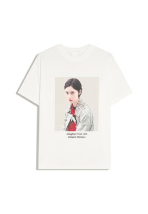 T-shirt blanc avec une photo centrée d'une femme portant une veste argentée et un haut rouge, le texte en dessous indique "Daughter From Hell (Gracie Abrams)"
