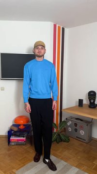 Sweatshirt azul de manga comprida, calças pretas, sapatos castanhos. Estilo casual com gola redonda. Tecido liso sem padrões visíveis.