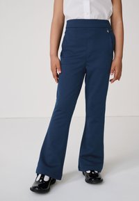 Pantalones acampanados azules hechos de tela suave, con cintura alta, bolsillos laterales y un pequeño detalle decorativo en la parte delantera.