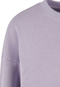 Felpa lavanda con scollo a girocollo a coste e tessuto testurizzato. Presenta una vestibilità morbida e un design senza cuciture alle spalle.