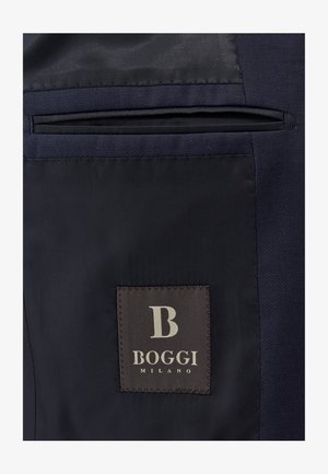 Navy fabric with a smooth, matte texture features a vertical pocket and a brown label with "BOGGI MILANO" in cream lettering.