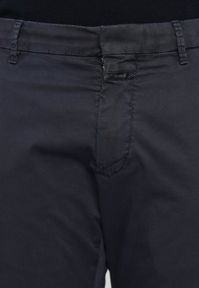 Pantalon bleu marine en tissu lisse, avec une fermeture éclair, des poches avant et une étiquette logo discrète sur la taille.