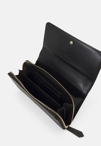 Portefeuille en cuir noir avec fermeture éclair et quincaillerie dorée. L'intérieur comprend plusieurs compartiments et fentes pour cartes pour une meilleure organisation.