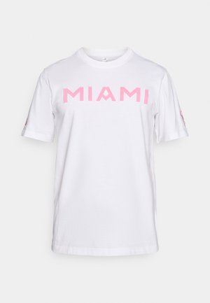 T-shirt en coton blanc avec l'inscription "MIAMI" en lettres roses épaisses, manches courtes et col rond. Design simple, texture lisse, dos uni.