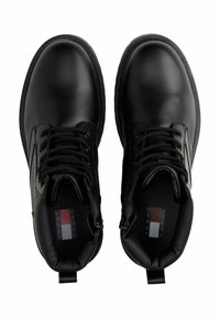Par de botas de tobillo de cuero negro con cordones, cuellos acolchados, puntas redondas y logo visible de Tommy Jeans en el interior.